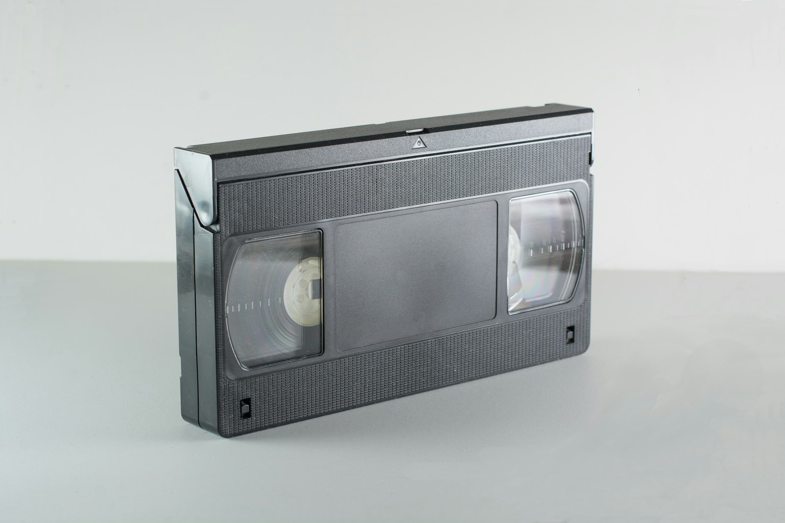Musta VHS-videokasetti harmaalla alustalla.